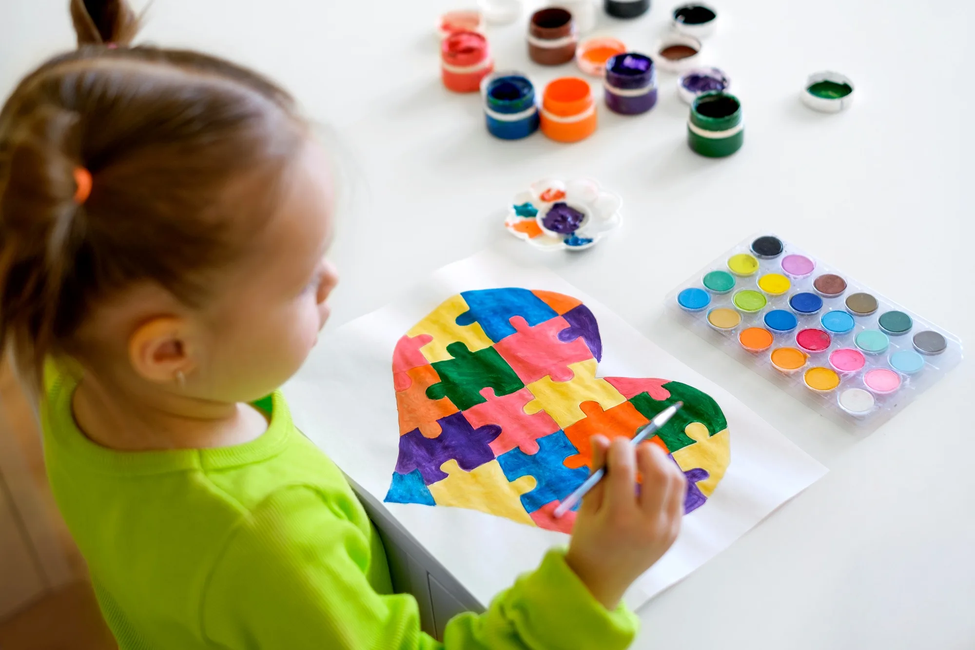 Baby draws a multicolored heart with gouache.
