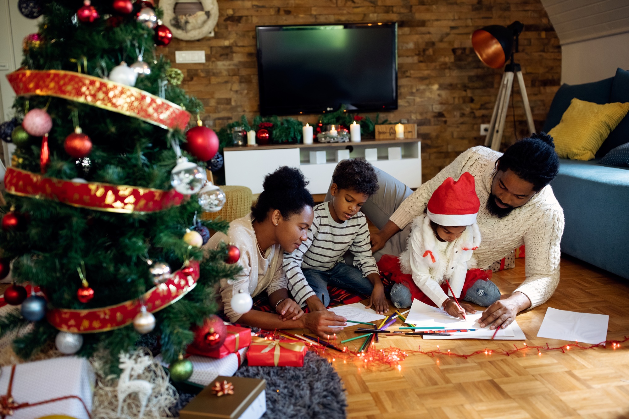Creative black family coloring on the paper while spending Christmas day at home.