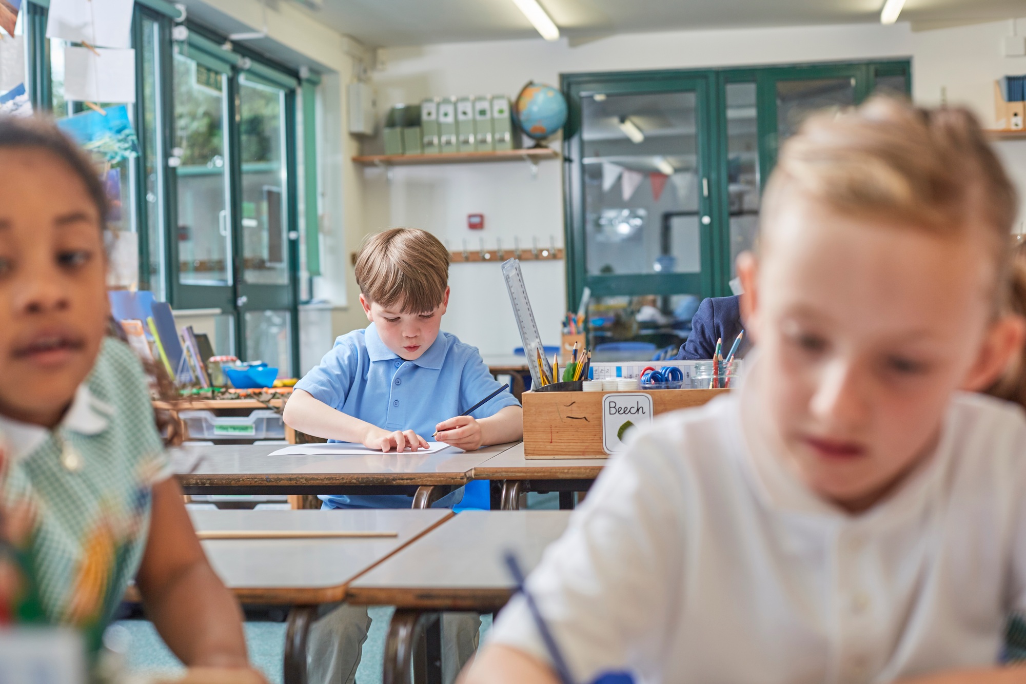 Primary schoolboy and girls doing schoolwork at classroom desks