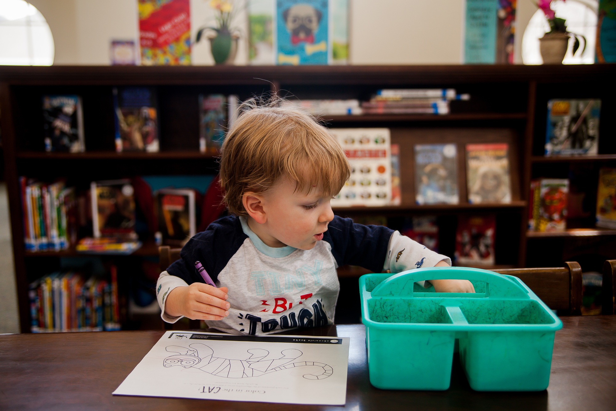 Toddler Boy coloring with crayons at the local library